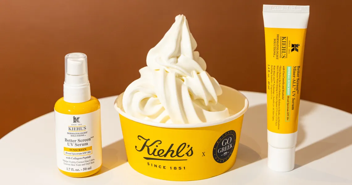 Frozen yogurt Better Summer Swirl у брендованому стакані Kiehl’s x Go Greek поруч із двома сонцезахисними засобами Better Screen