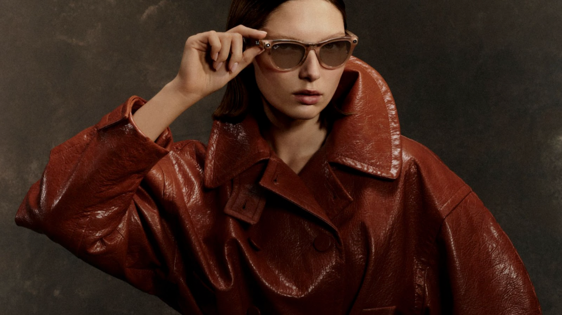 Модель у напівпрозорих окулярах Ray-Ban Meta та об’ємному коричневому шкіряному плащі