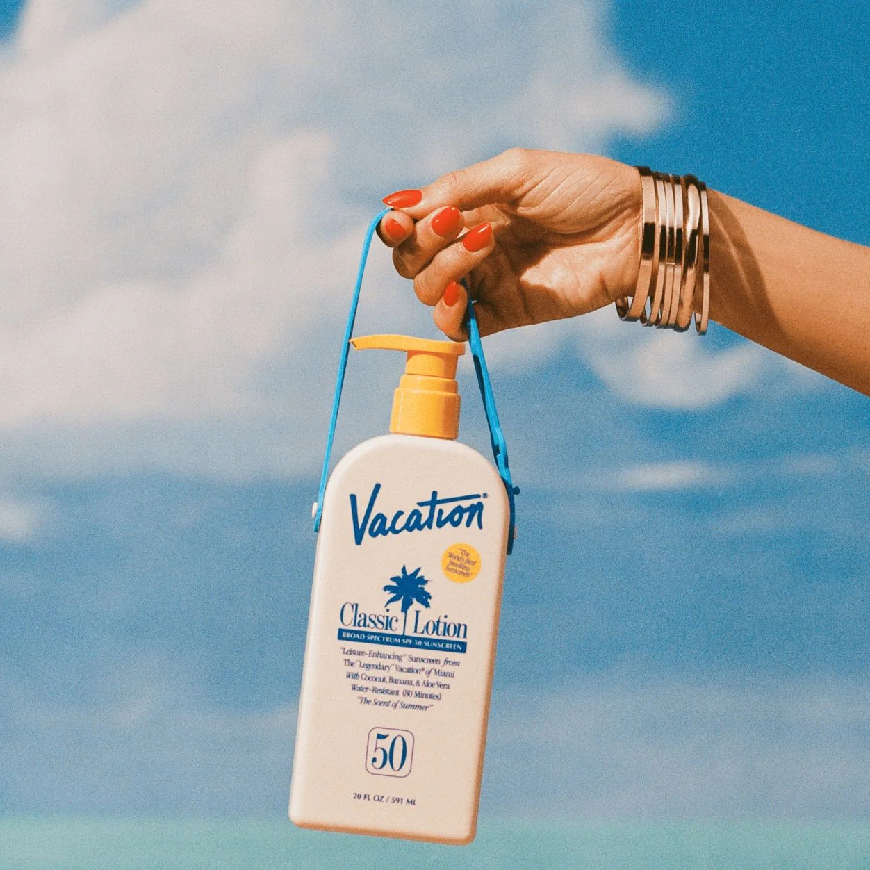 Vacation Classic Lotion SPF 50 у руці на фоні моря і неба